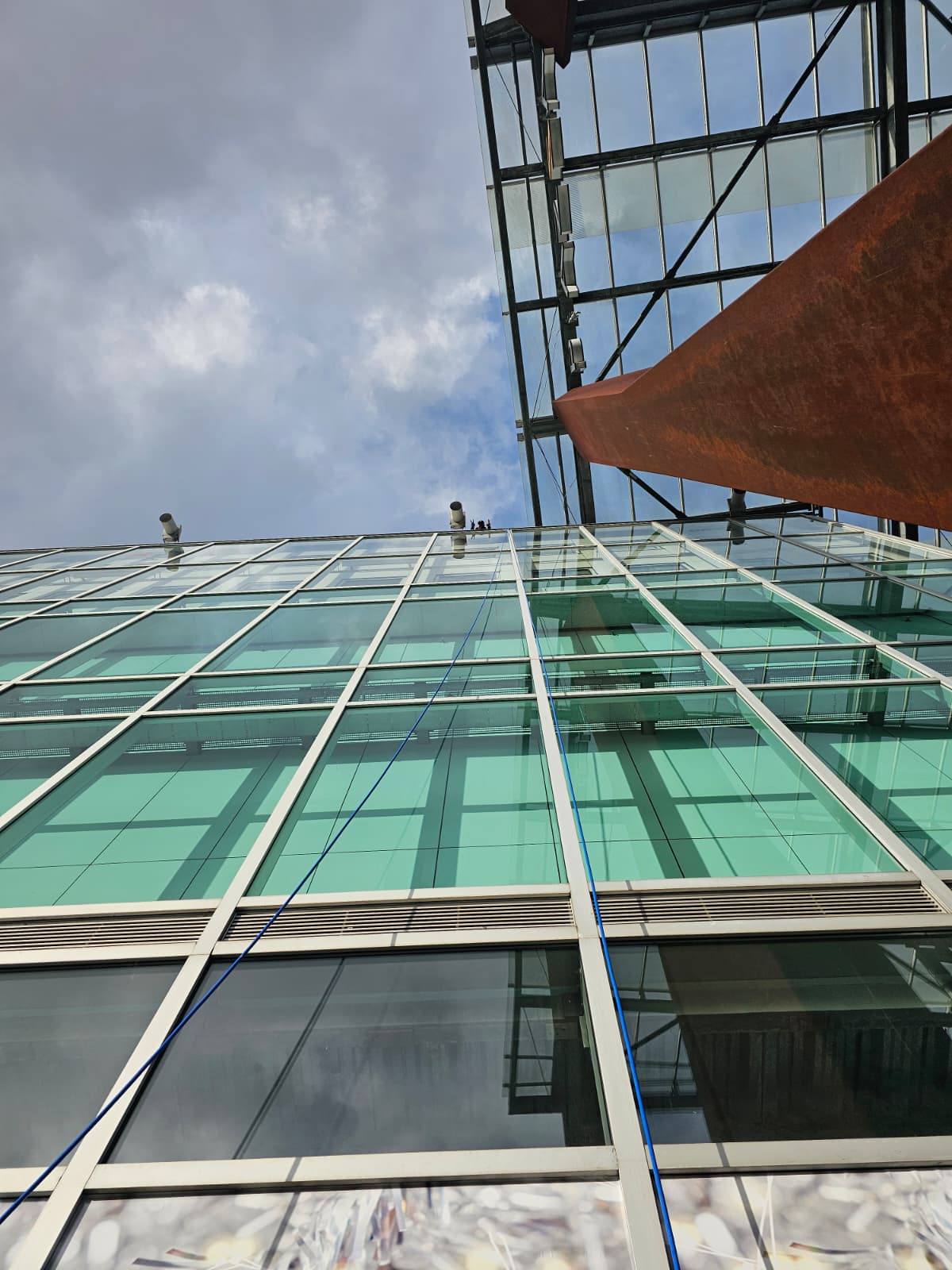 Hoge glasgevel gereinigd met osmose-telescoopsteel