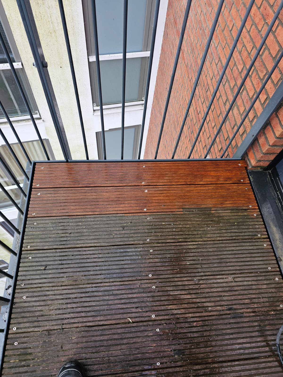 Houten vlonder half gereinigd met softwash — links nog vervuild, rechts schoon