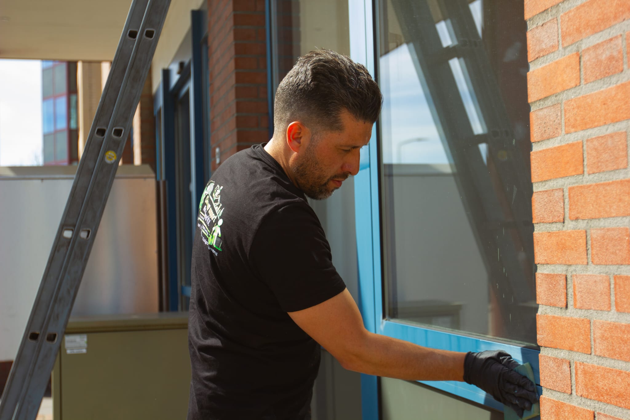 Medewerker maakt een raam streeploos schoon bij een bedrijfspand